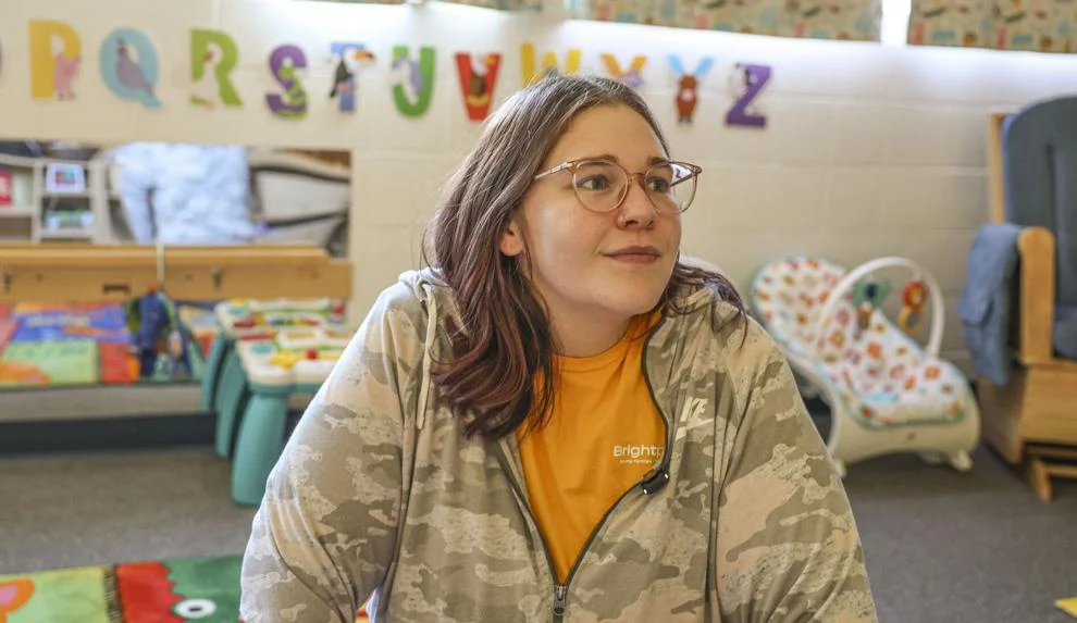 A young woman is shown inside a childcare room