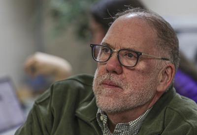 A middle-aged man with facial hair and glasses is shown