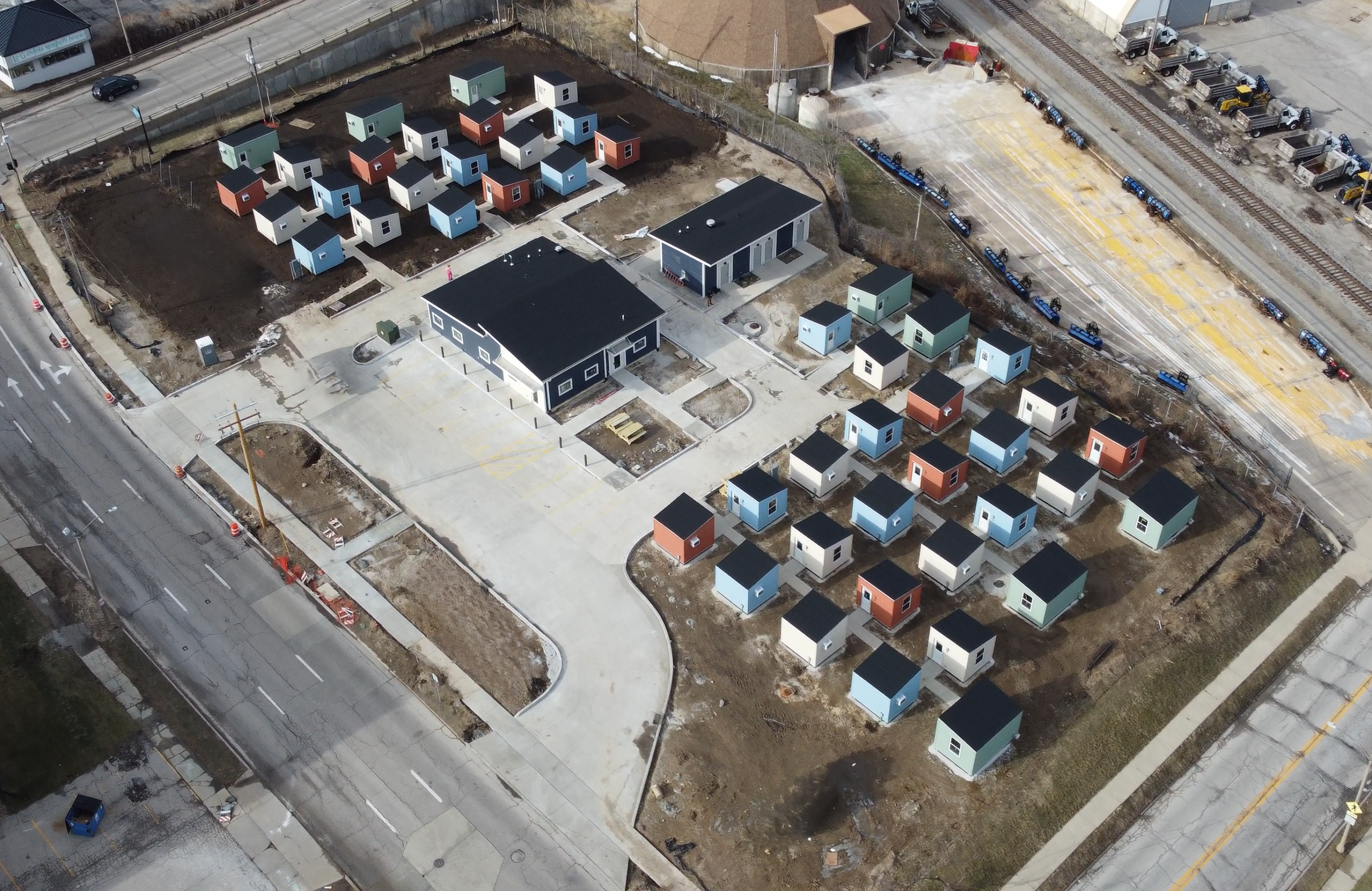 An overhead drone shot of a shelter village with small homes situated around a community taking up a square block of property.