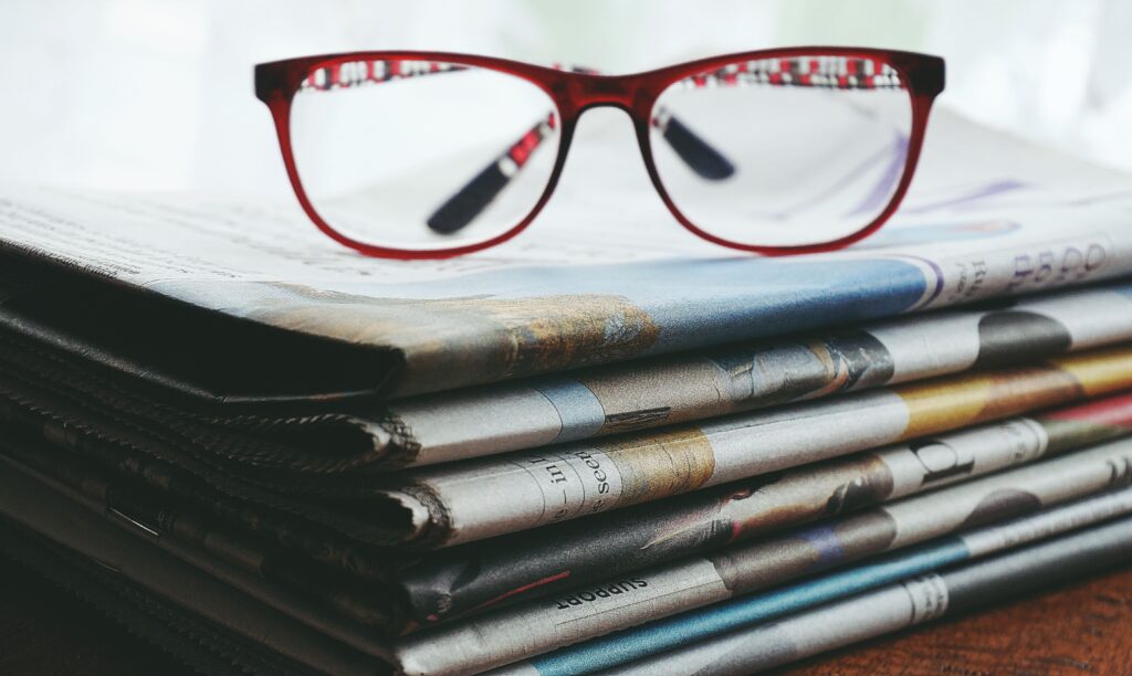 A pair of glasses rests on a stack of newspapers